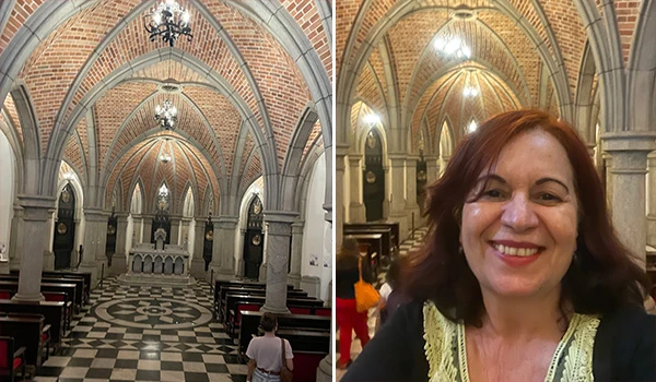 Interior da Cripta da Igreja da Sé em São Paulo com arquitetura em arcos de pedra e piso em padrão xadrez, ao lado Deusa Rodrigues em primeiro plano durante a visita ao local religioso.