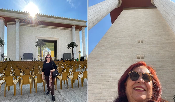 Deusa Rodrigues posando em frente a uma grande construção com cadeiras organizadas para um evento ao ar livre, durante a visita guiada ao Templo de Salomão.