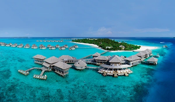 Vista paradisíaca de resort sobre as águas cristalinas, rodeado por ilhas tropicais e com bangalôs luxuosos, ideal para férias inesquecíveis.
