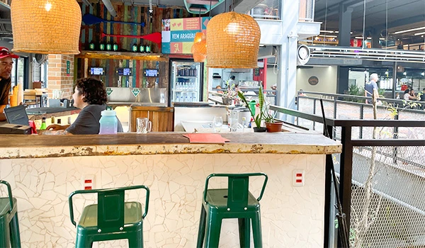 Imagem de um bar com decoração moderna, iluminação aconchegante e detalhes de porcelanas e plantas, ideal para quem busca um ambiente agradável.
