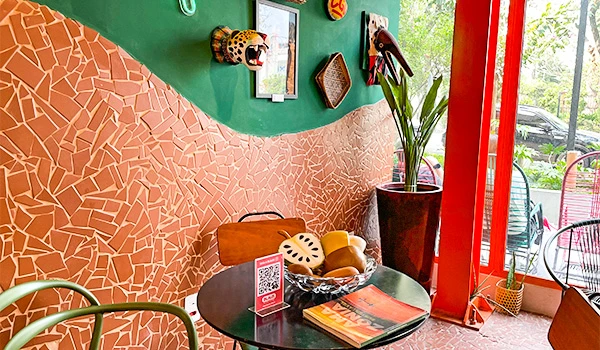 Ambiente de sorveteria com decoração vibrante, parede colorida com mosaico, plantas e detalhes artesanais, ideal para desfrutar de momentos relaxantes e snacks.