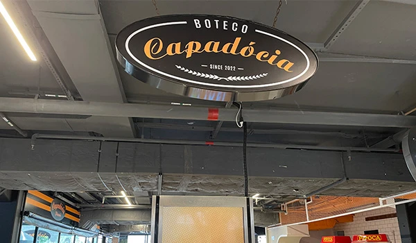 Interior do Boteco Capadócia, um espaço moderno e acolhedor para apreciar bebidas e petiscos no estilo boteco, com destaque para o logo no teto.