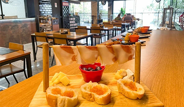 Buffet de café da manhã com pães, geleias e frutas em uma cafeteria moderna com espaço aberto e ambiente acolhedor. Mercado de Santo Amaro restaurantes.