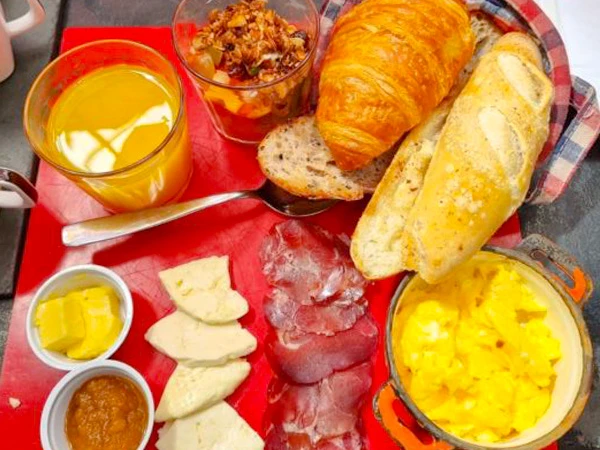 Deliciosa tábua de café da manhã com croissant, pães variados, queijos, presunto, manteiga e suco, café da manhã em São Paulo
