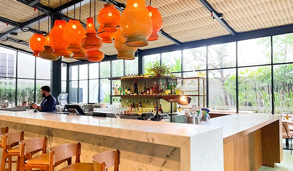 Interiores de um bar moderno com iluminação cativante e decoração contemporânea, mostrando o balcão e prateleiras com bebidas.
