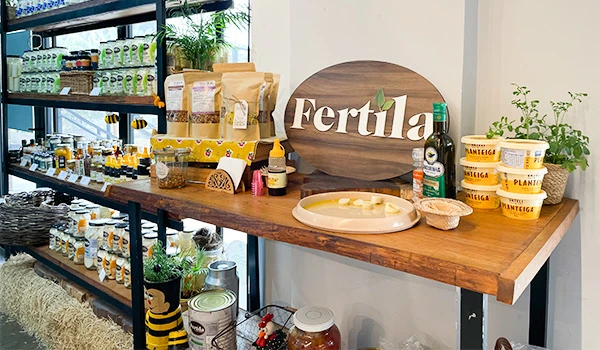 Mostruário de produtos naturais e orgânicos na loja Fertila, com alimentos saudáveis, suplementos, e itens para fertilidade, em ambiente bem iluminado e decorado com plantas.