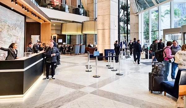 Recepção de hotel moderna com pessoas fazendo check-in e filas, ambiente acolhedor e elegante, ideal para viajantes.