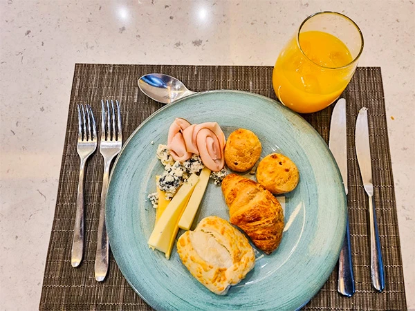 Prato de café da manhã em São Paulo com frios, queijos, pães e suco de laranja. Uma refeição deliciosa e saudável para começar o dia.