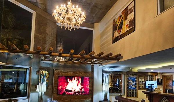 Lobby do Meu Hotel em Boituva, com aconchegante com lareira, iluminação sofisticada e decoração elegante, ideal para momentos de relaxamento e convivência.