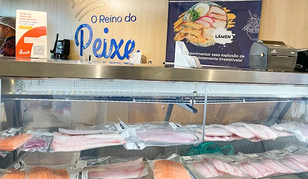 Exposição de peixes frescos na peixaria 'O Reino do Peixe' com corte de peixe e variedades de pescados embalados.