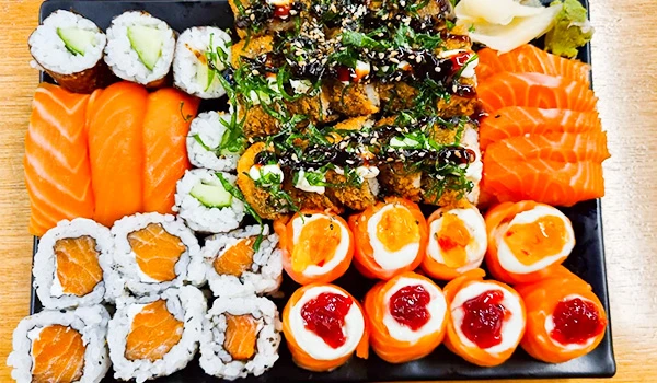 Imagem de variedade de sushis, incluindo sashimi de salmão, rolinhos de alga com peixe e sushi recheado com cream cheese, representando uma refeição japonesa deliciosa. Mercado de Santo Amaro restaurantes.