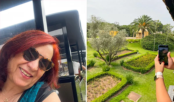 Deusa Rodrigues sorri para a câmera em uma área externa. Ao lado, uma pessoa fotografa um jardim com gramados, canteiros bem cuidados, arbustos e palmeiras.