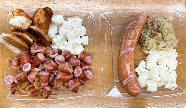 Comida tradicional brasileira, incluindo queijo, salsicha, batatas e chucrute, em pratos de vidro. Mercado de Santo Amaro restaurantes.