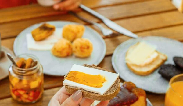 Deliciosa mesa de café da manhã com pães, geléia e frutas. Um pão com manteiga e geleia de frutas é destaque, perfeito para começar o dia.