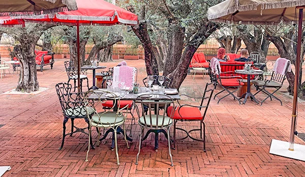 Foto de mesas, cadeiras e guarda-sóis na área externa com árvores no Hotel Rosewood, um dos hotéis mais caros de SP.