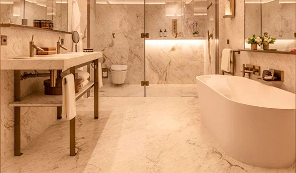 Foto de um banheiro todo revestido de mármore, com linda banheira e toda decoração em branco.