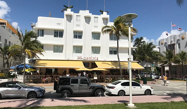 Vista do famoso Hotel Carlyle em Miami Beach, arquitetura art déco, com palmeiras e carros em destaque. Atrações de South Beach.