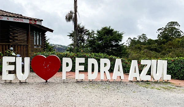 Placa com a frase 'Eu amo Pedra Azul' em uma paisagem natural, destacando a beleza da região na Rota das Montanhas Capixabas.