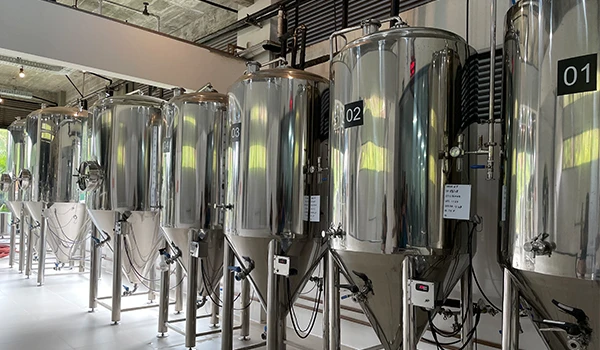 Imagem de tanques de fermentação em uma cervejaria, mostrando equipamentos modernos em ambiente industrial. Cervejaria Dus Grillo na  Rota das Montanhas Capixabas.