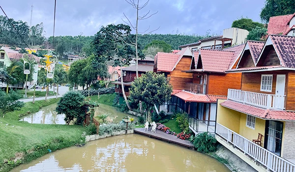 Vista de um Hotel China Parque, com chalés de madeira, lagoa e vegetação ao redor, ideal para um dia tranquilo na natureza.