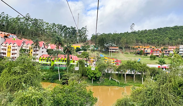 Vista panorâmica do Hotel China Park em meio à natureza, com casas coloridas ao fundo e um lago à frente, ideal para relaxar e aproveitar a paisagem.