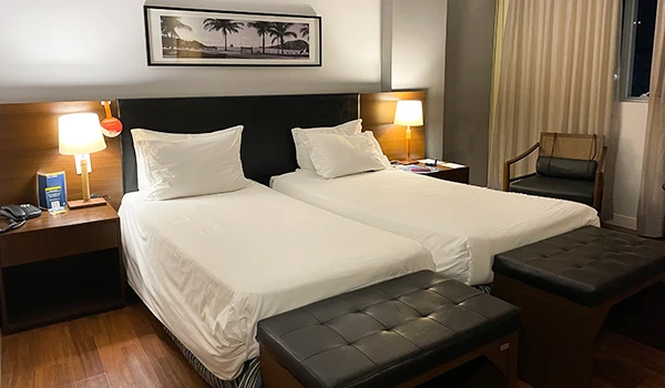 Quarto de hotel moderno com camas de solteiro, décor sofisticado e iluminação aconchegante, ideal para descanso e lazer.