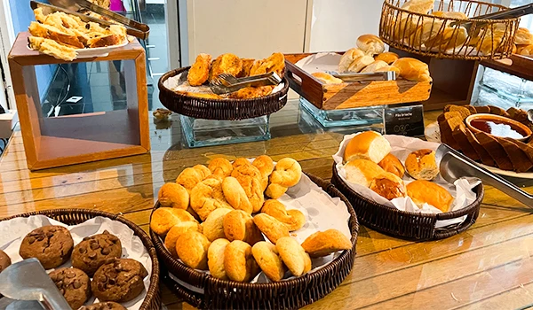 Selecionado variado de pães e doces em uma mesa de buffet, incluindo salgadinhos, pãezinhos e bolachas, foto do café da manhã do Hotel Golden Tulip Vitória.
