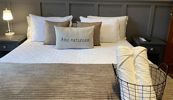 Quarto aconchegante com cama decorada, travesseiros e toalhas. Hotel Natureza Eco Lodge, na Rota das Montanhas Capixabas.