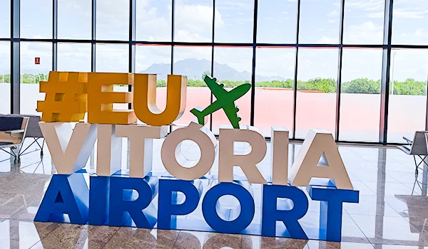 Instalações do Aeroporto de Vitória com a arte de letras coloridas que incluem a hashtag #EUVitoriaAirport, transmitindo uma mensagem de acolhimento aos viajantes.