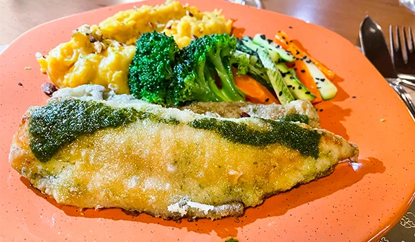 Prato saboroso de filé de peixe com crosta, acompanhado de brócolis, purê de batata e vegetais grelhados. Uma refeição saudável e deliciosa.