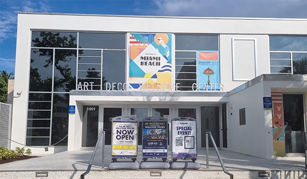 Imagem do Art Deco Welcome Center destacando a fachada e banners de eventos especiais. Atrações de South Beach.