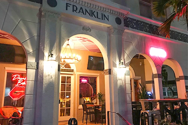 Entrada do restaurante Franklin à noite, iluminada com luzes de néon, ambiente convidativo. Uma das atrações de South Beach.