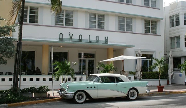 Imagem de um carro clássico em frente ao Hotel Avalon, destacando a arquitetura art déco e a cultura vintage da região. Uma das atrações de South Beach.