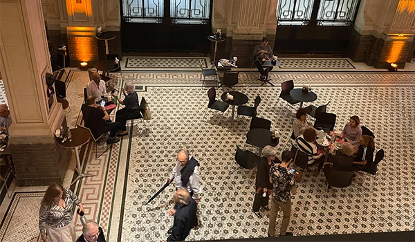 Cenário de um café elegante, com clientes desfrutando de momentos sociais em um ambiente acolhedor e bem decorado, com piso de ladrilhos detalhados. Dicas da Sala São Paulo.