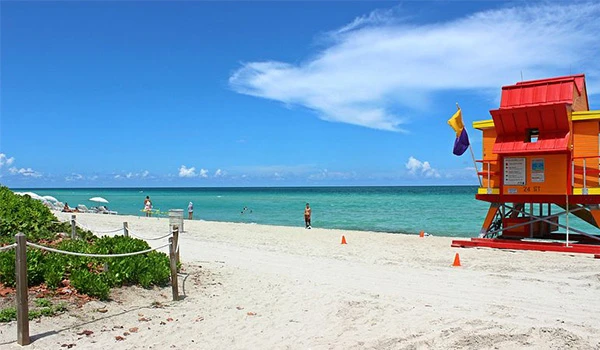 Praia de areia branca com guarda-vidas colorido e mar azul. Local ideal para relaxar e aproveitar o clima ensolarado. Uma das atrações de South Beach.