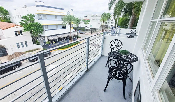 Varanda elegante em Miami com mesa e cadeiras, vista para a rua em dia nublado. Apartamentos para alugar são uma das atrações em South Beach.