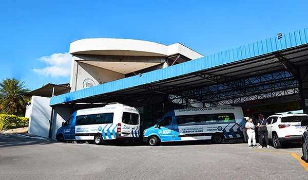 Frota de vans de transporte aeroporto em frente ao terminal com céu limpo e azul, estacionamento em Guarulhos Airport Park.