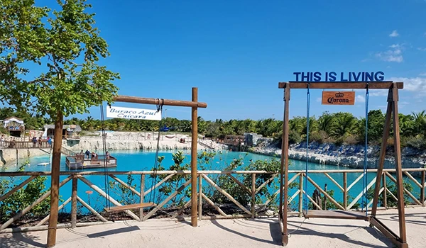 Praia com balanços suspensos em um cenário paradisíaco, rodeada pela água azul e vegetação exuberante. Ideal para relaxar e aproveitar momentos de lazer.