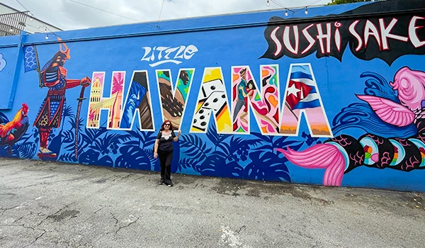 Mural colorido na Calle Ocho, destacando a palavra 'HAVANA' em grandes letras, com elementos artísticos relacionados à cultura local.