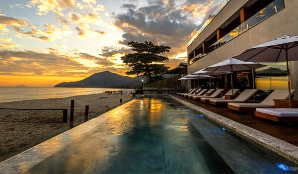 Piscina do hotel Duke Beach com pôr do sol ao fundo, no post Onde ficar em Maresias.