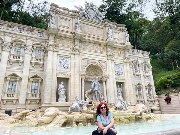 Deusa Rodrigues em Serra Negra em frente da Fontana de Trevi, destacando a beleza arquitetônica do local e a alegria da visita.