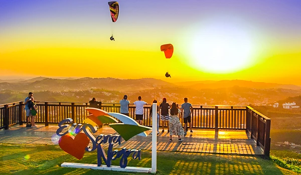 Pessoas aproveitando um pôr do sol com visualização de balões de ar quente e um cenário natural, em um local com estrutura de observação ao ar livre, depois de observar a Fontana di Trevi de Serra Negra.