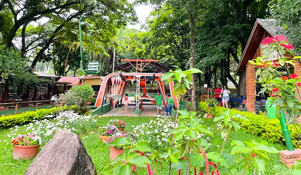 Um parque verde e alegre com brinquedos para crianças, flores coloridas e famílias se divertindo. Um ótimo local para lazer e recreação ao ar livre.