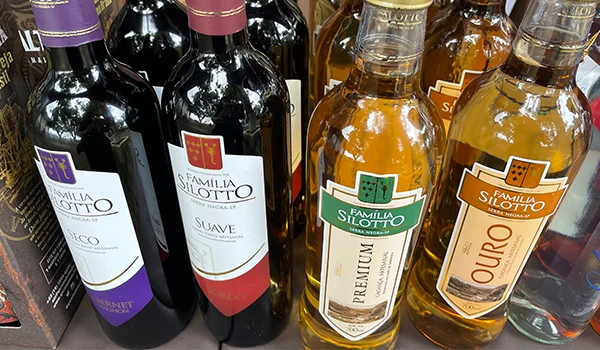 Vinhos da Família Silotto em uma prateleira, incluindo varietais como Cabernet, Suave, Premium e Ouro. Ideal para momentos especiais e harmonização de sabores.