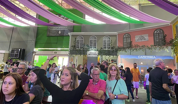 Evento cultural com público animado em ambiente decorado, destacando barracas de comida e atrações diversas. Ideal para divulgação de festivais.