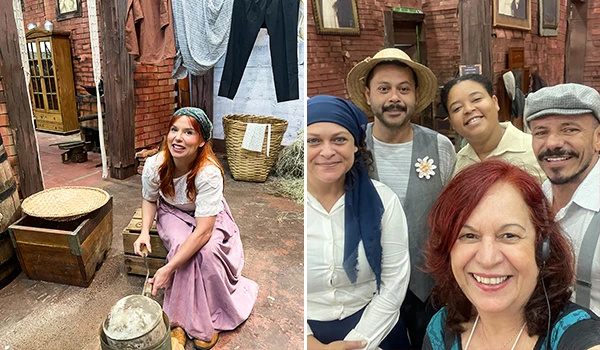 Grupo de pessoas em um ambiente que remete à vida rural, com destaque para uma mulher que está realizando uma atividade manual, vestindo roupas de época. típica Festa da Uva de Jundiaí.