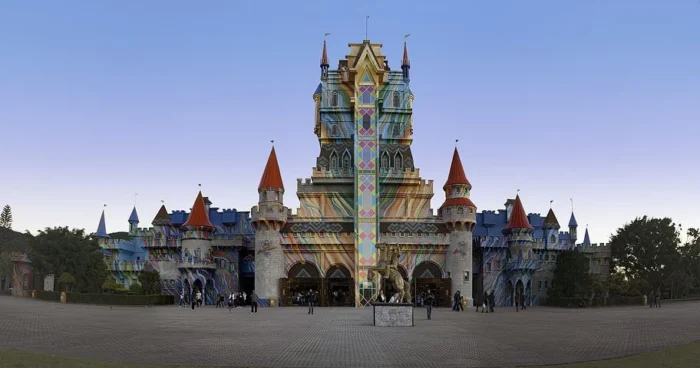 Vista panorâmica do castelo colorido com torres e detalhes arquitetônicos em um dia claro, representando um ambiente mágico e encantador. Ideal para curtir Parques e Hotéis no Carnaval,