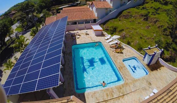 Imagem da piscina da Pousada Jovimar, em Aparecida com sistema de energia solar, destacando os painéis solares ao lado da piscina. Um dos lugares baratos para Lua de Mel em SP.