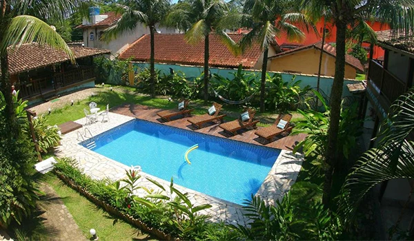 Imagem de uma piscina rodeada por natureza e espreguiçadeiras em um ambiente tranquilo, ideal para relaxar e aproveitar os dias ensolarados.