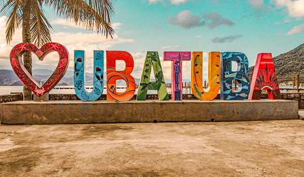 Letreiro colorido com a inscrição 'I ❤️ UBATUBA' em um cenário natural, destacando a beleza da cidade de Ubatuba.